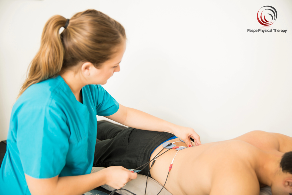 A physical therapist using electrical stimulation to treat a patient with lumbar radiculopathy in New York.