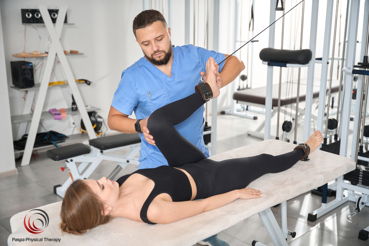 A physical therapist helping a patient exercise her hamstring to treat a strain in New York.